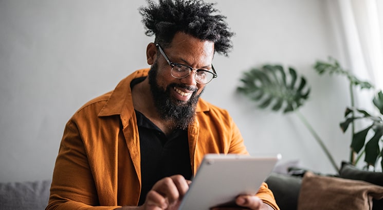 A man smiles as he scrolls on a tablet computer